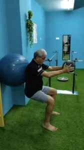 Patient performing balance exercises on a BOSU board with resistance bands during physiotherapy session